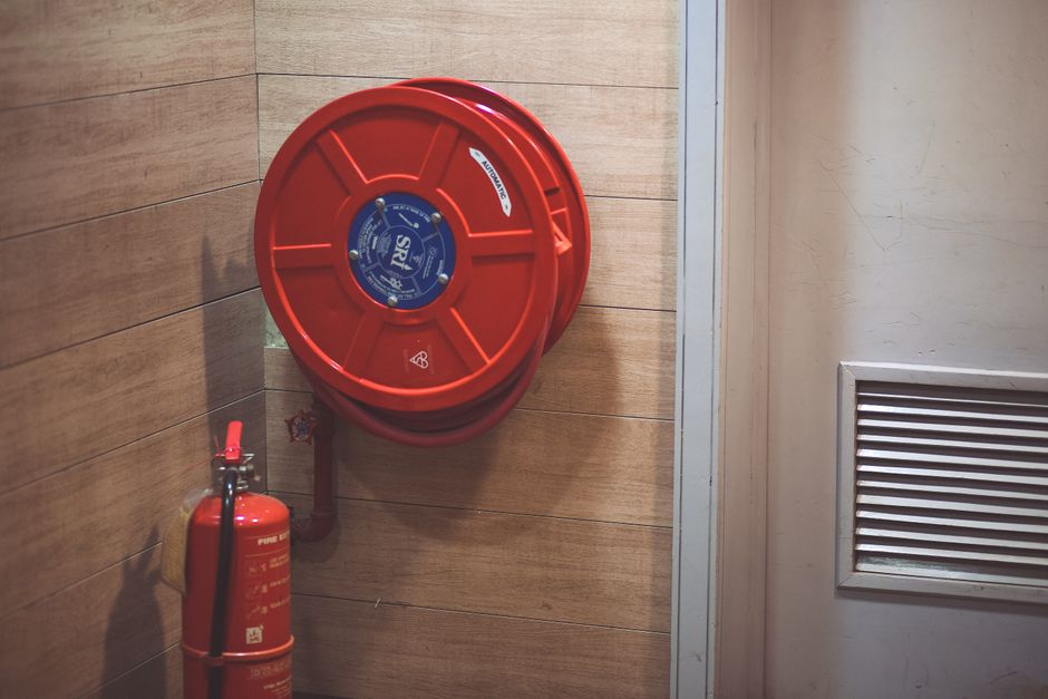 建物の隅にある赤い消火ホースリールと消火器。